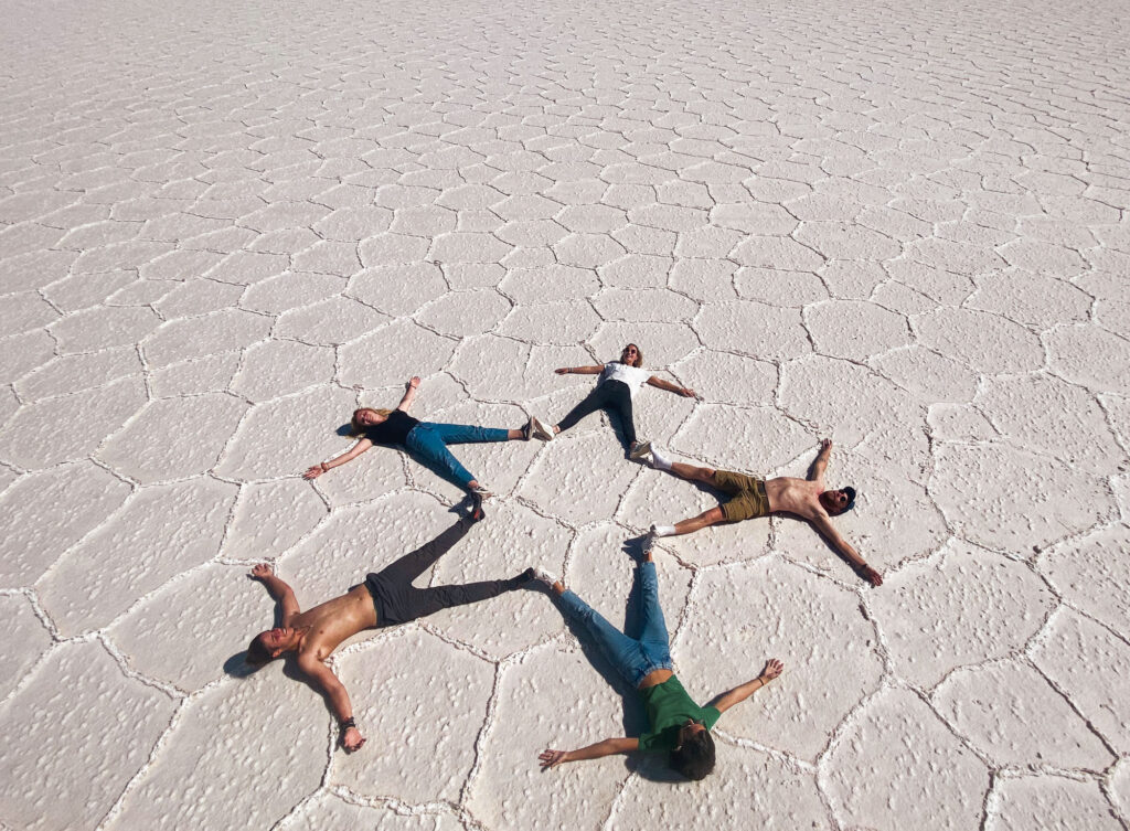 Group forming a star with their bodies on Salar de Uyuni, Bolivia.