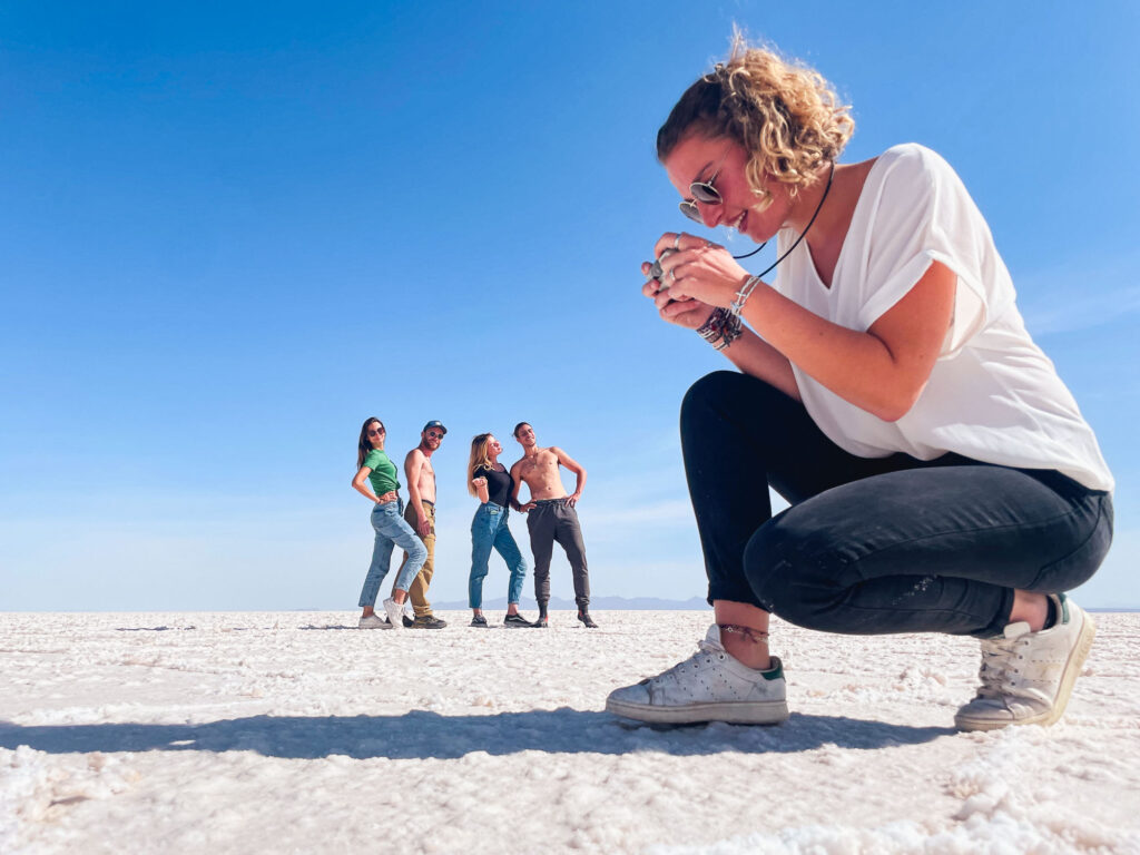 Creative photo of travelers using perspective and illusions in the salt desert of Salar de Uyuni, Bolivian Altiplano.