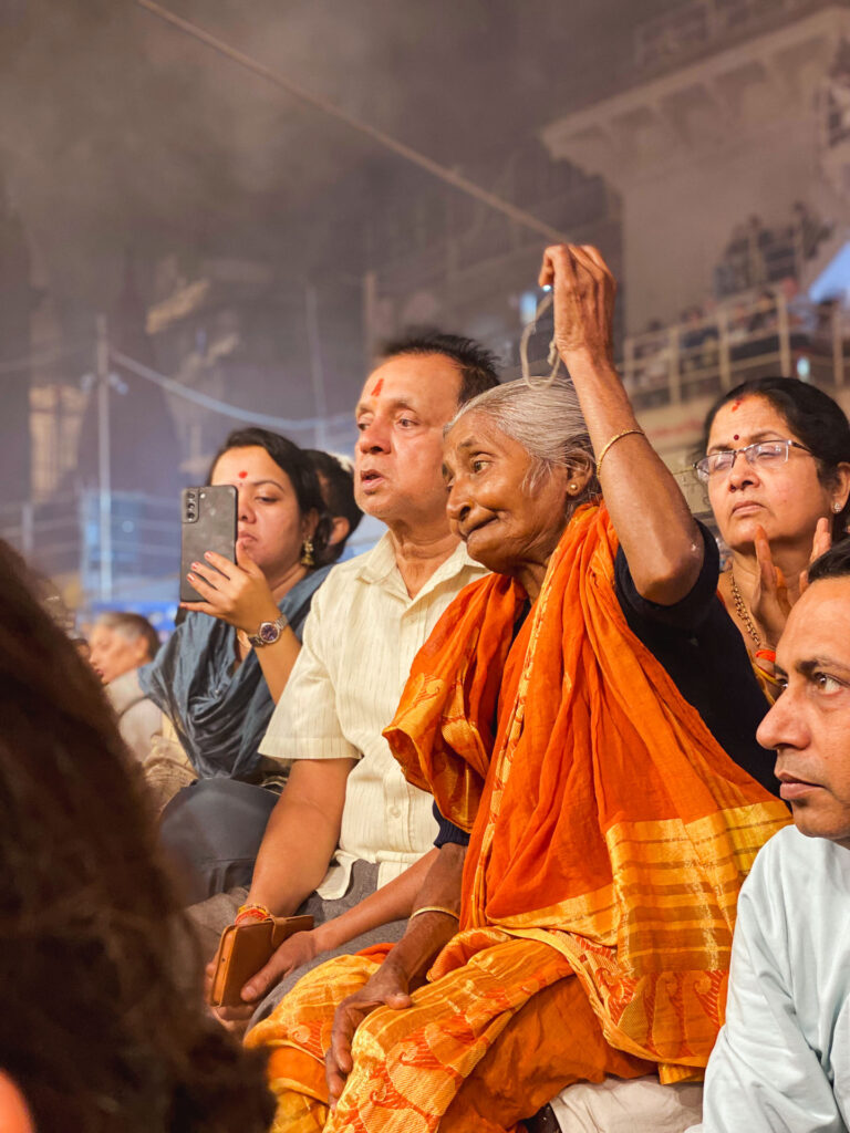 Elderly woman participating in a religious ceremony at sunset on the banks of the Ganges in Varanasi.