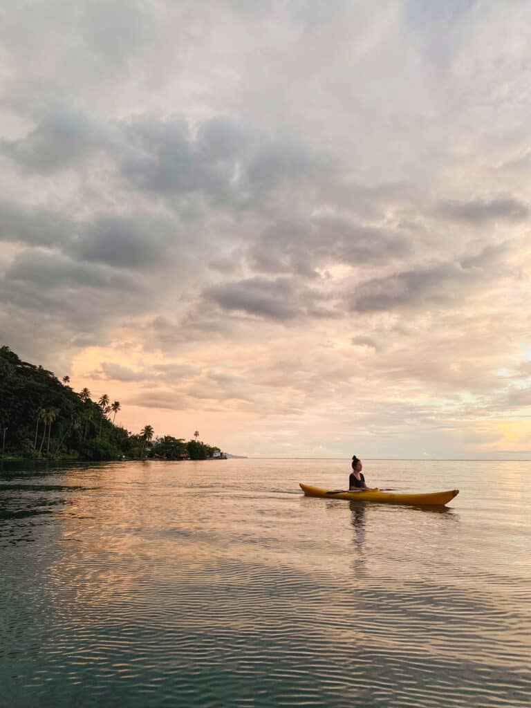 Eva en canoë sur le lagon de Taha’a au coucher du soleil, Polynésie française.