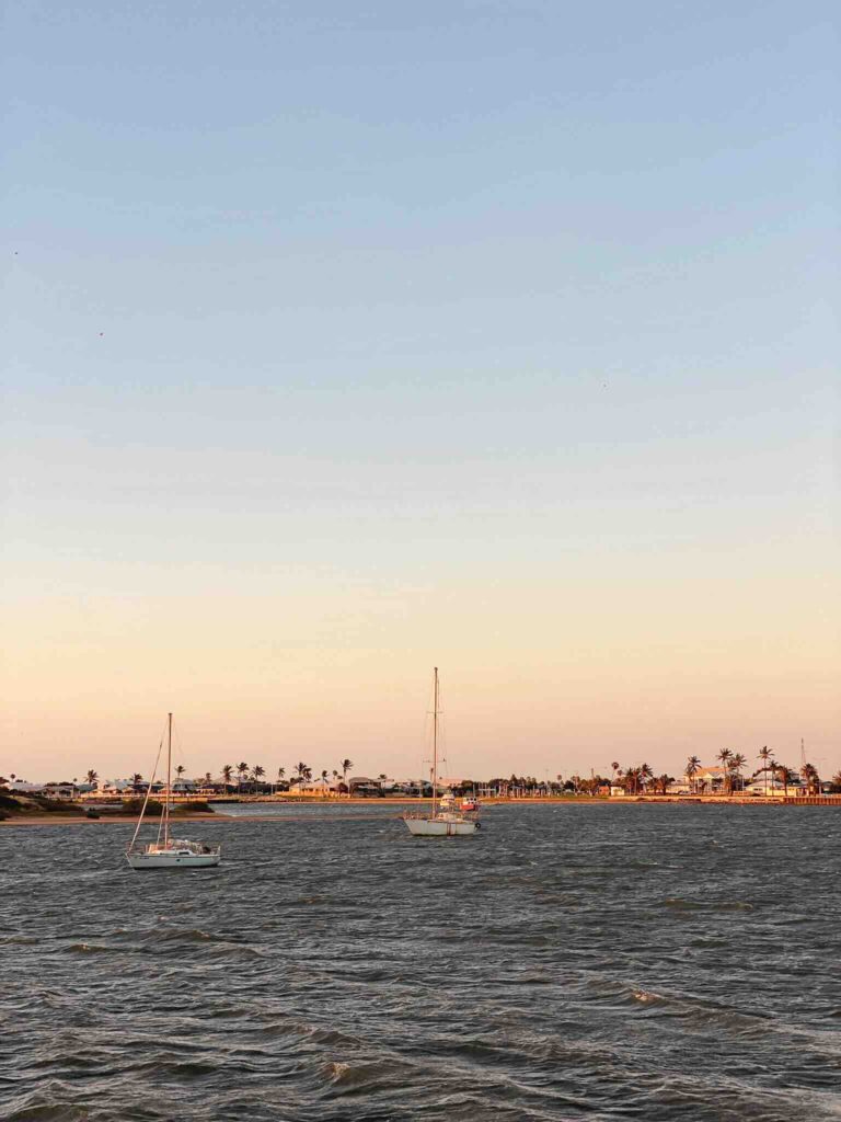 Boats at Carnarvon harbor at sunset with an orange sky during our Perth to Exmouth road trip.