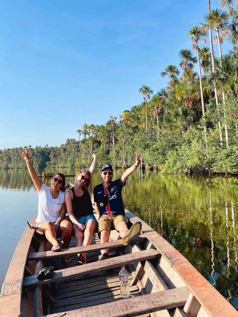 Three friends on a boat on a lake surrounded by tropical trees in the Peruvian Amazon.