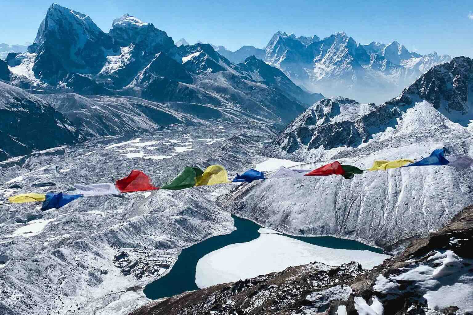 Spectacular panorama from Gokyo Ri on the Three Passes Trek in Nepal: Gokyo Lake, Himalayan peaks, and Nepali prayer flags.