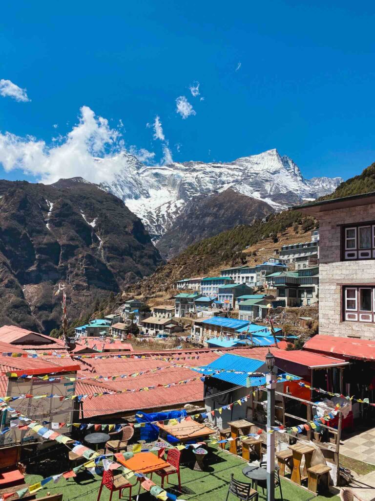 Panoramic view of Namche Bazaar village and snowy Himalayan peaks from a terrace, Three Passes Trek, Nepal.