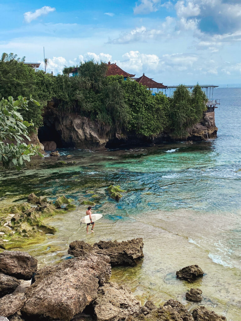 Surfer about to enter the water at the tip of Nusa Ceningan, Indonesia.