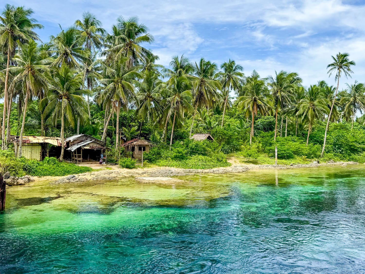 Paysage idyllique à Siargao Philippines, entre eau turquoise, habitations et forêt tropicale.