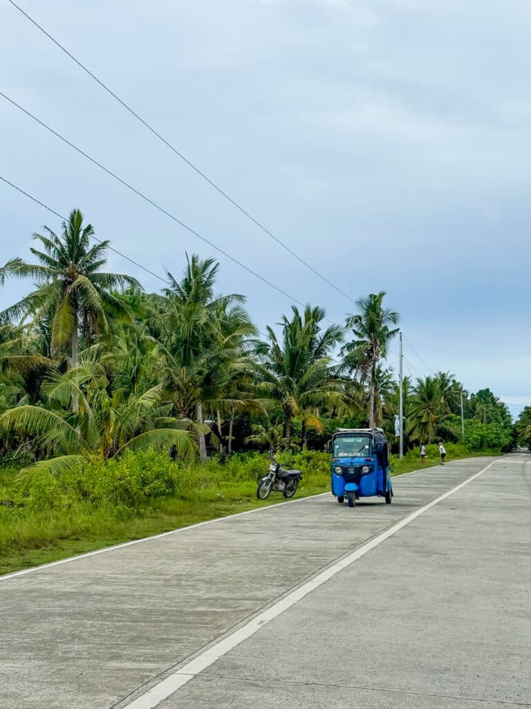 Tuktuk sur une route bordée de cocotiers à Siargao Island. 