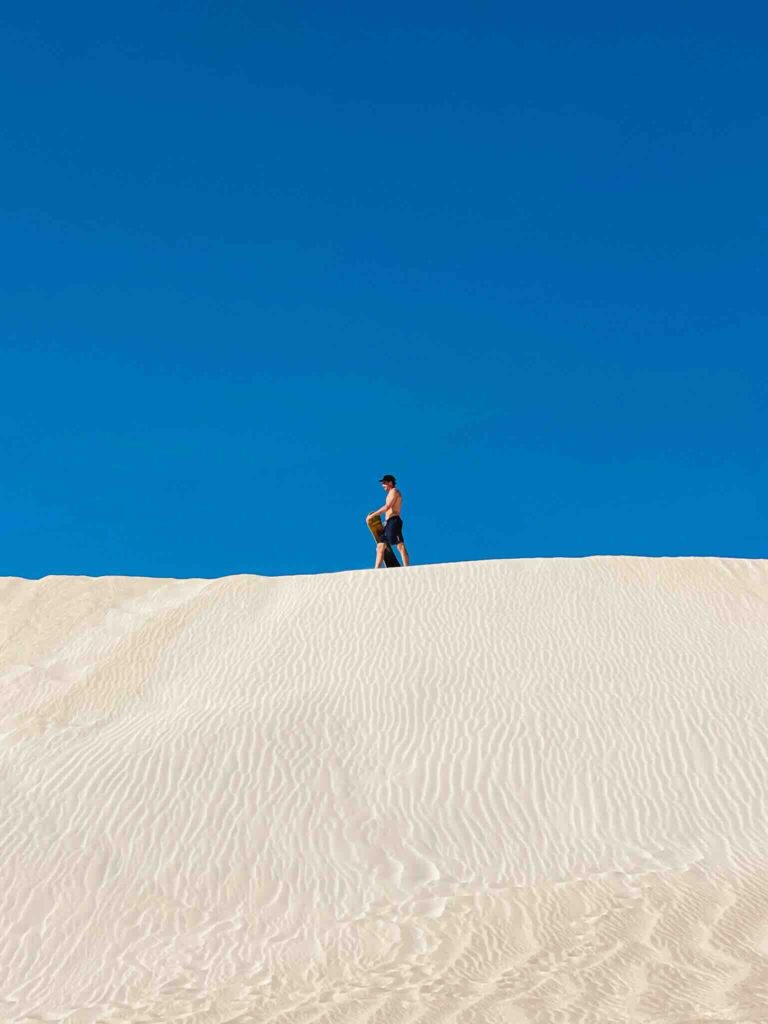 Sandboarding on the white sand dunes of Lancelin in Western Australia during a Perth to Exmouth road trip.